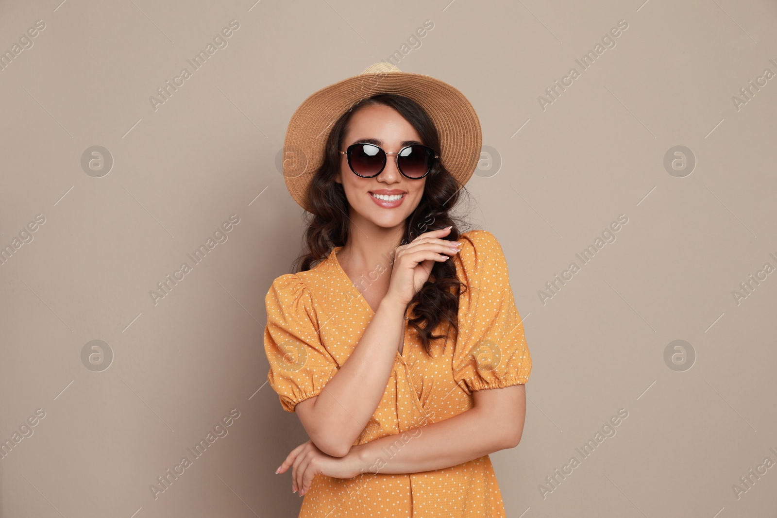 Photo of Beautiful young woman with straw hat and stylish sunglasses on beige background