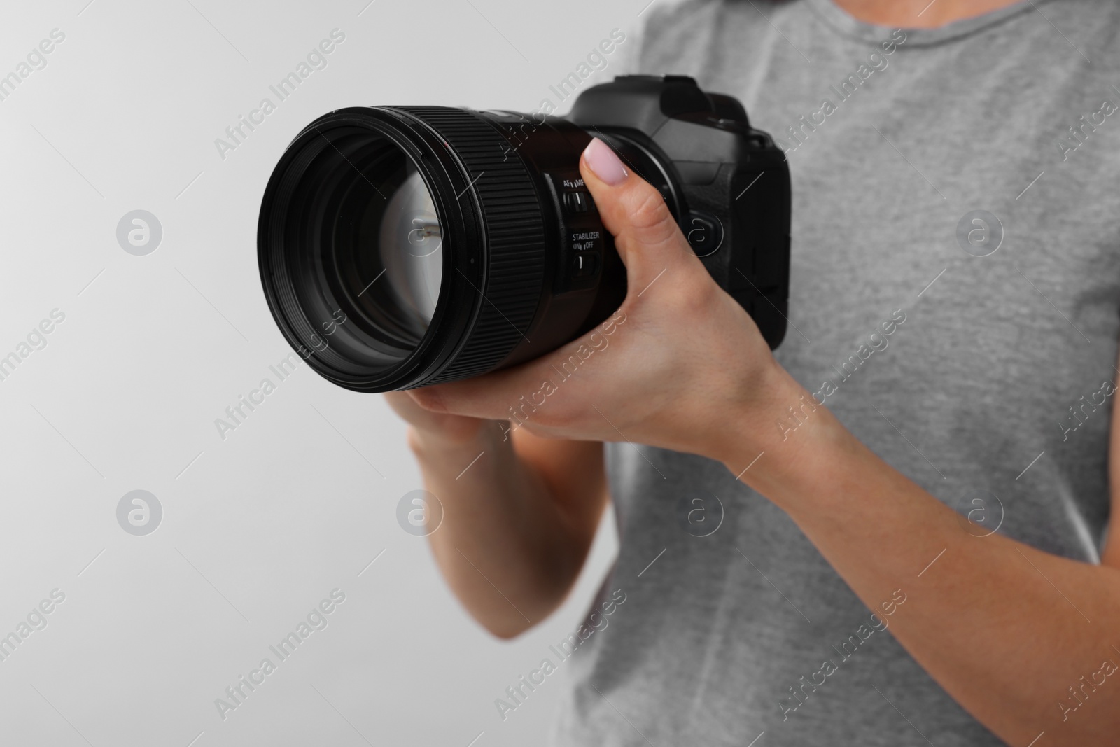 Photo of Photographer with camera on light grey background, closeup