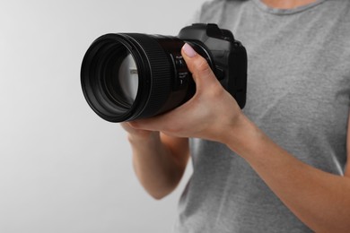 Photo of Photographer with camera on light grey background, closeup