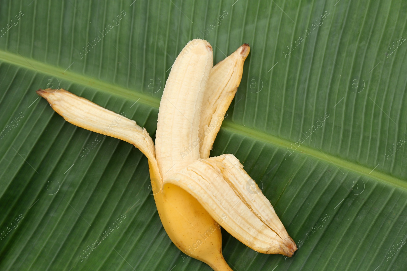 Photo of One delicious banana on fresh green leaf, top view