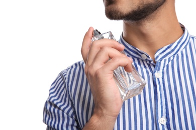 Young man applying perfume on white background, closeup