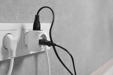 Many different electrical power plugs in sockets on grey wall indoors, closeup. Space for text