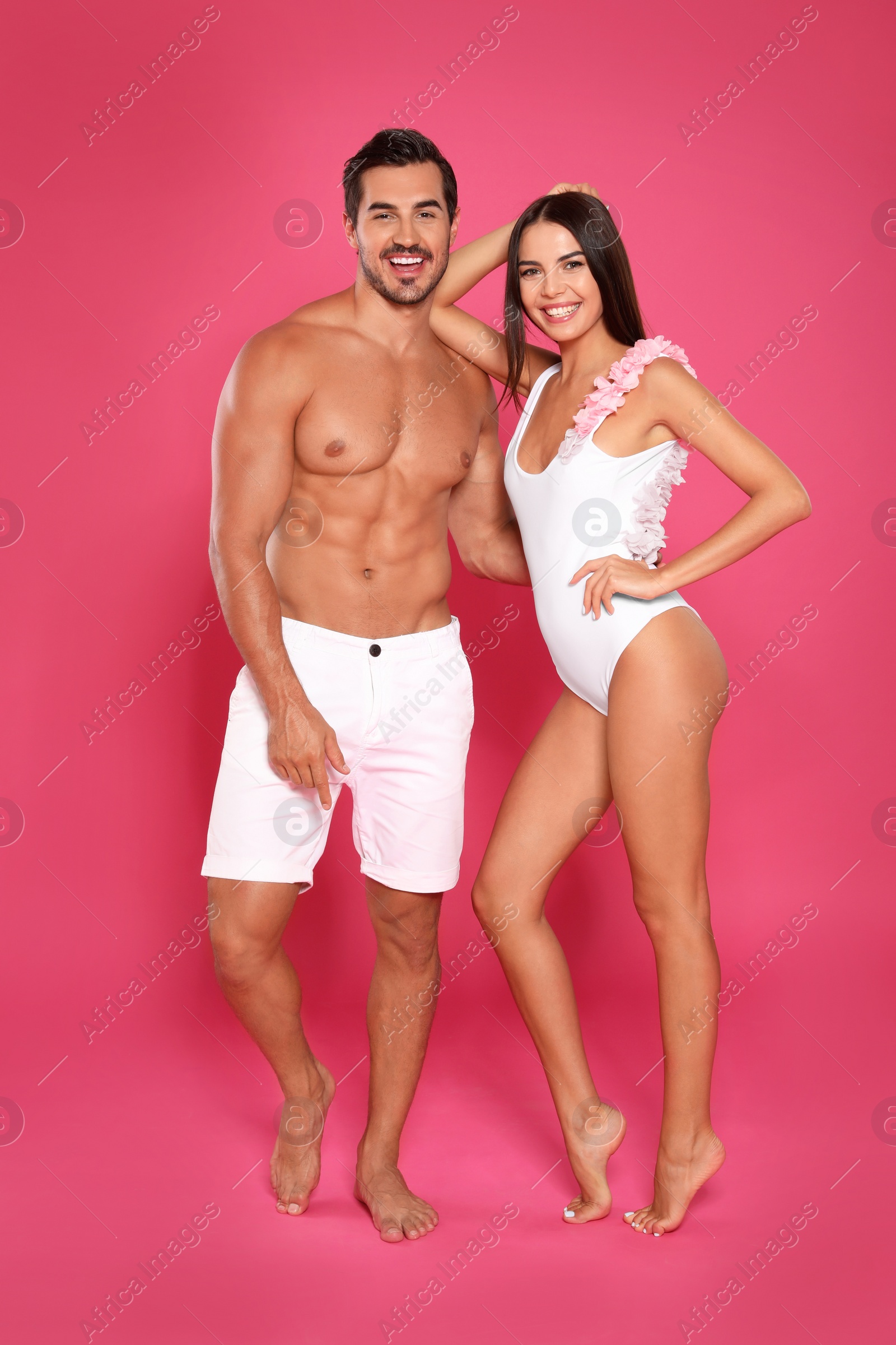 Photo of Young attractive couple in beachwear on pink background