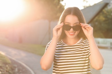 Photo of Beautiful smiling woman in sunglasses outdoors, space for text