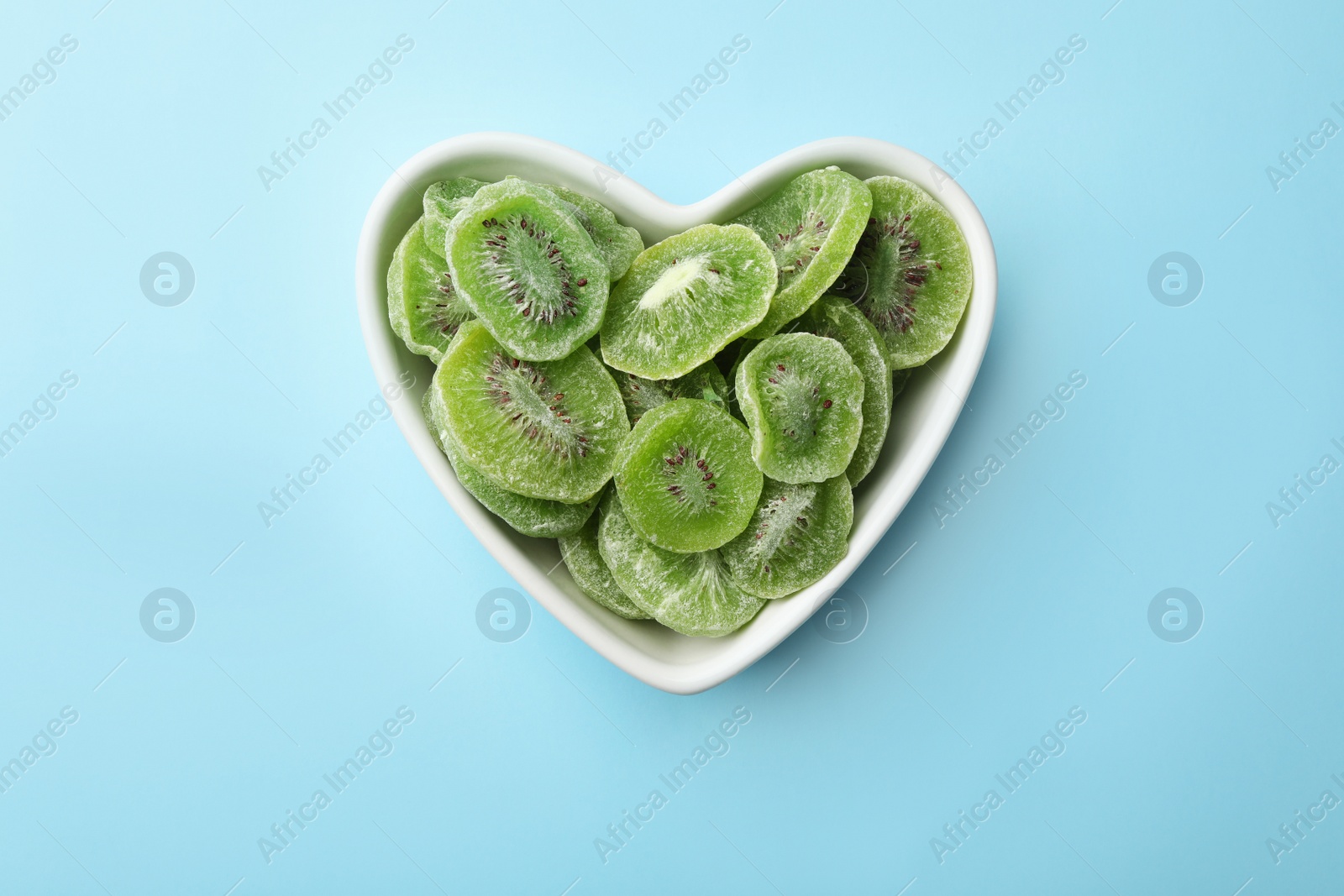 Photo of Bowl with slices of kiwi on color background, top view. Dried fruit as healthy food