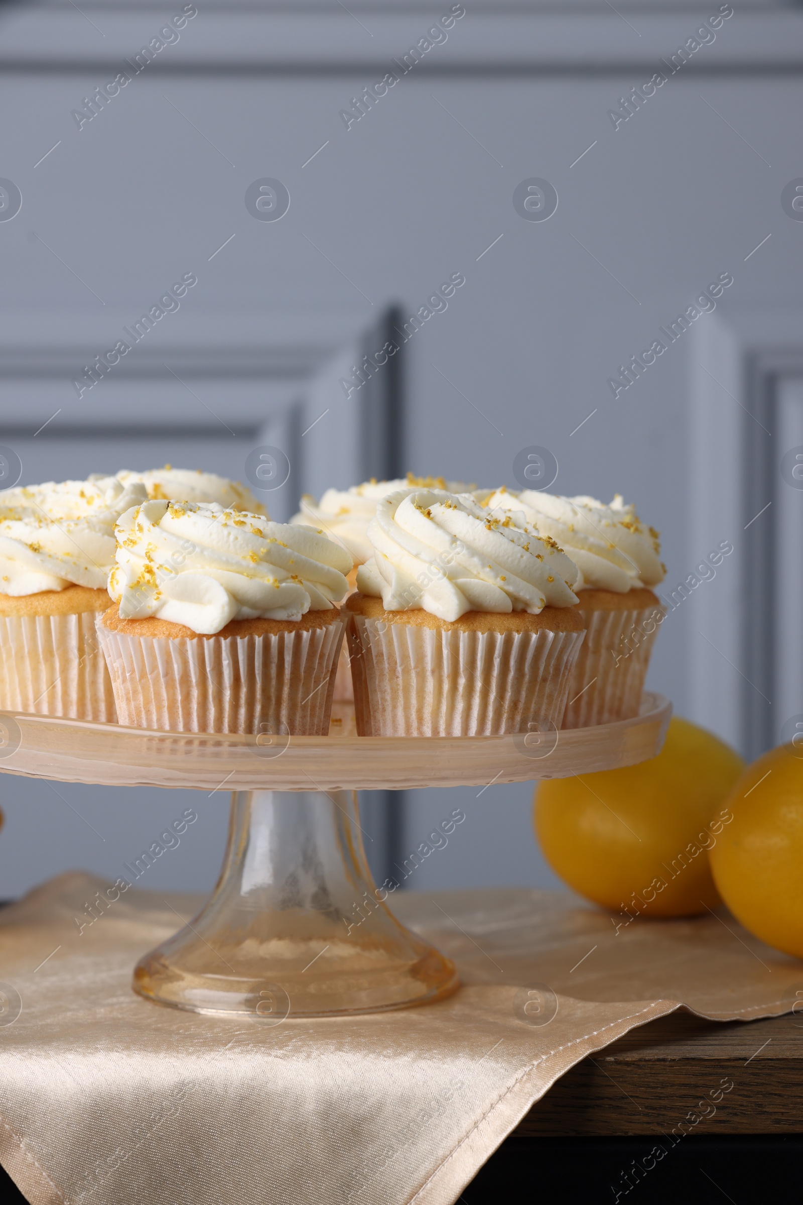 Photo of Delicious lemon cupcakes with white cream on table