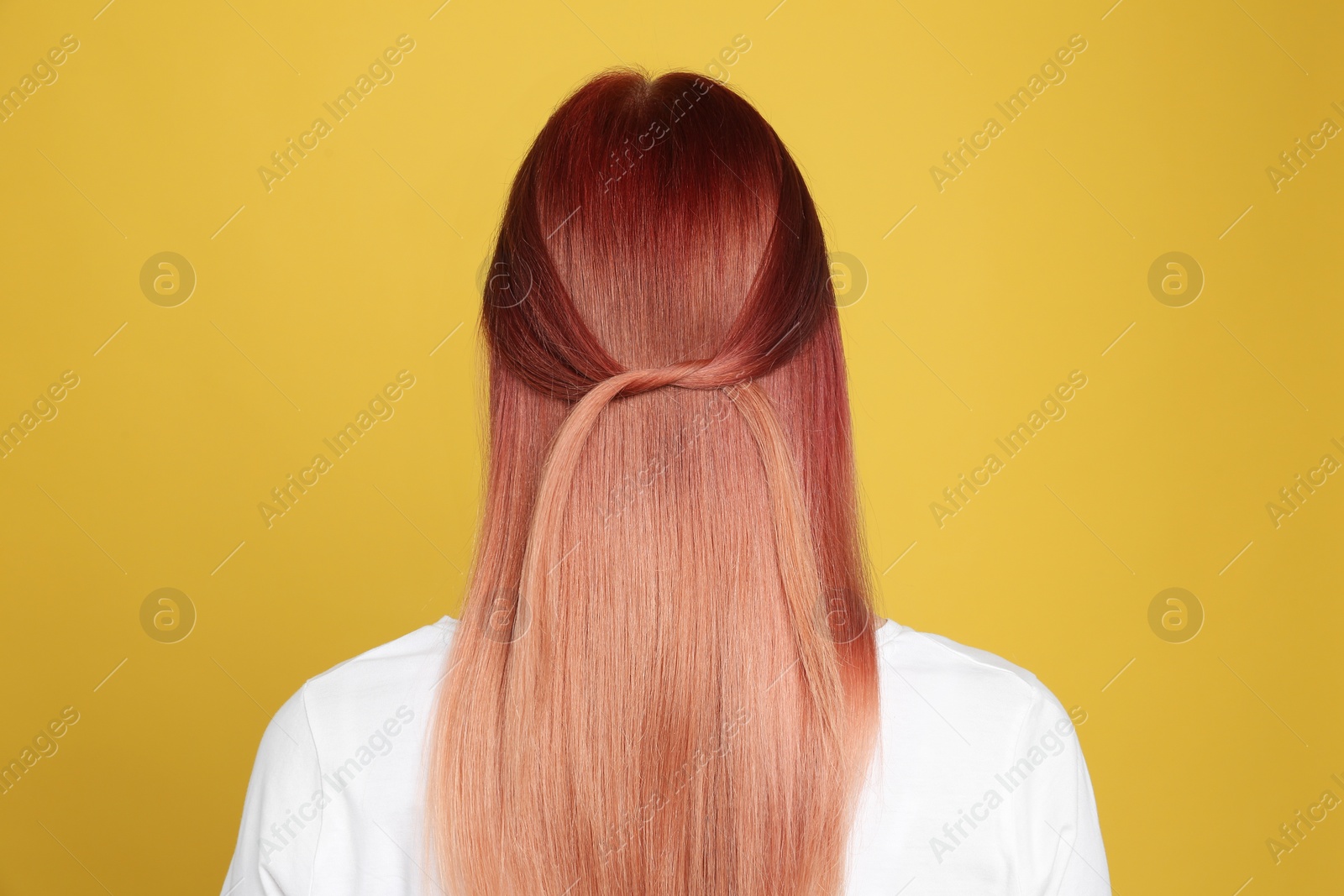 Photo of Woman with bright dyed hair on yellow background, back view