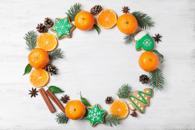 Photo of Frame made with tasty Christmas cookies and tangerines on white wooden background, flat lay. Space for text