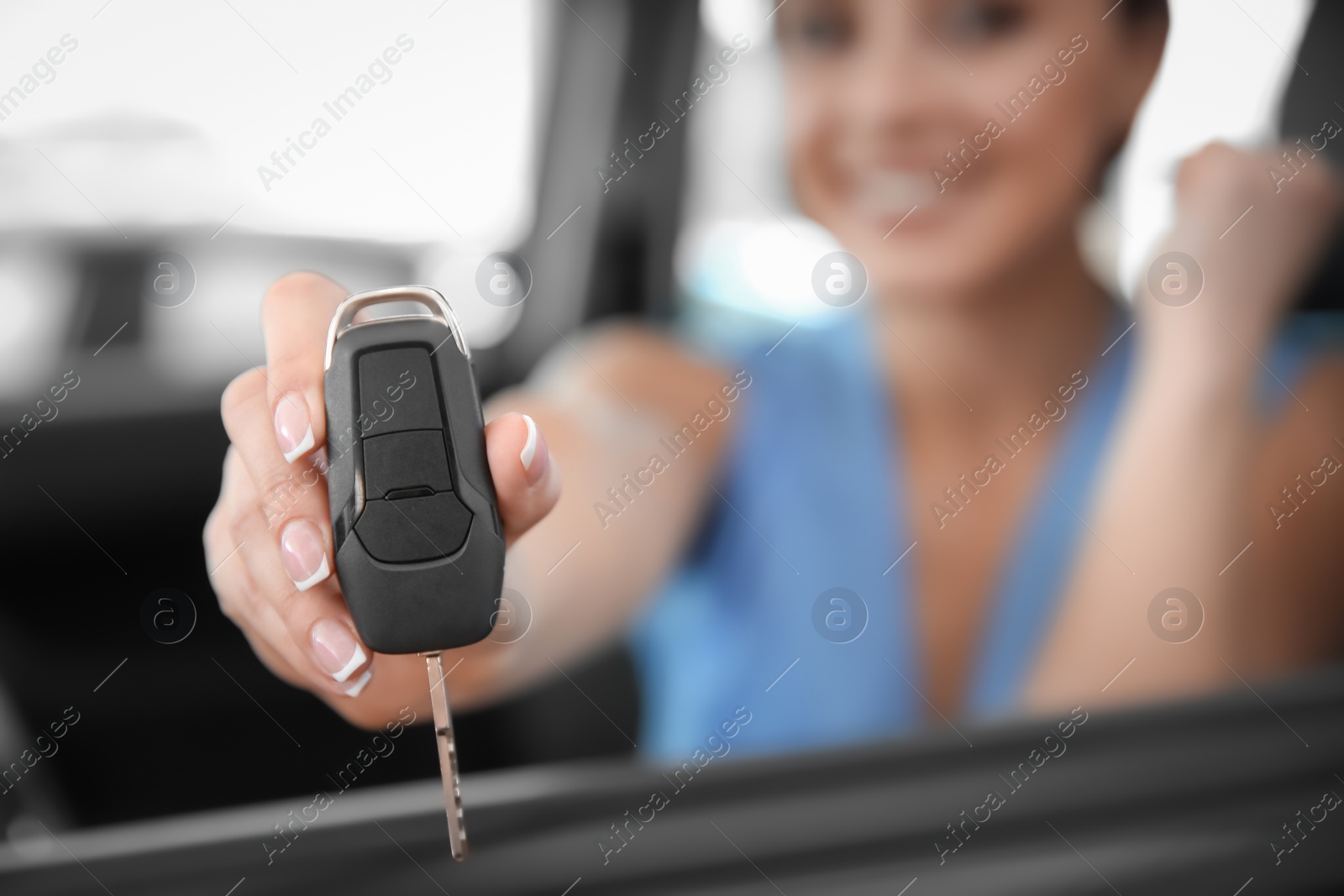 Photo of Young woman with key sitting in driver's seat of new car, closeup