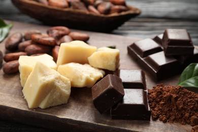 Photo of Organic cocoa butter and chocolate on wooden table, closeup