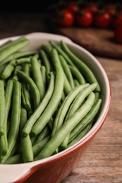 Raw green beans in baking dish on wooden table, closeup