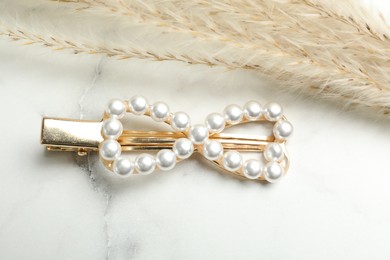 Beautiful gold hair clip and spikelets on white marble table, flat lay