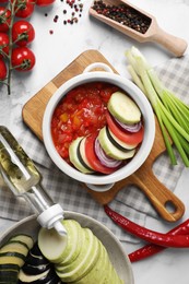 Dressing for delicious ratatouille and different vegetables on white marble table, flat lay