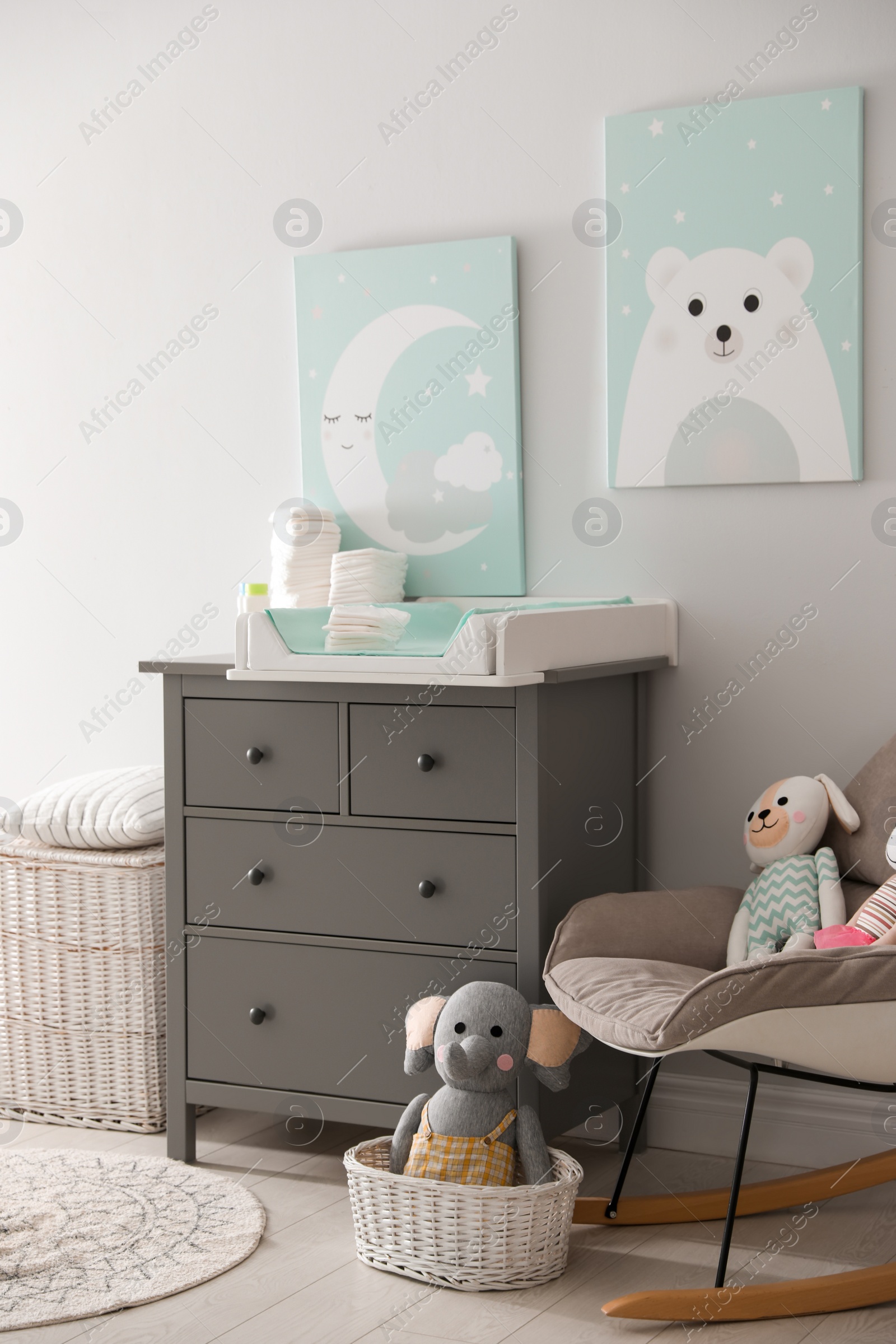 Photo of Chest of drawers with changing tray and pad in baby room. Interior design