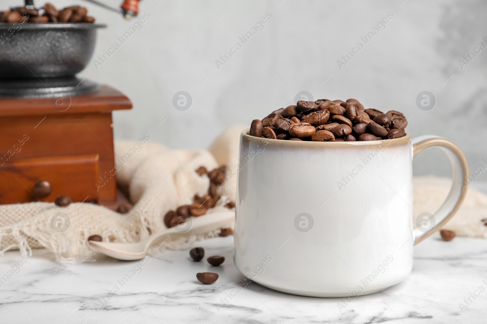 Photo of Ceramic cup with coffee beans on marble table