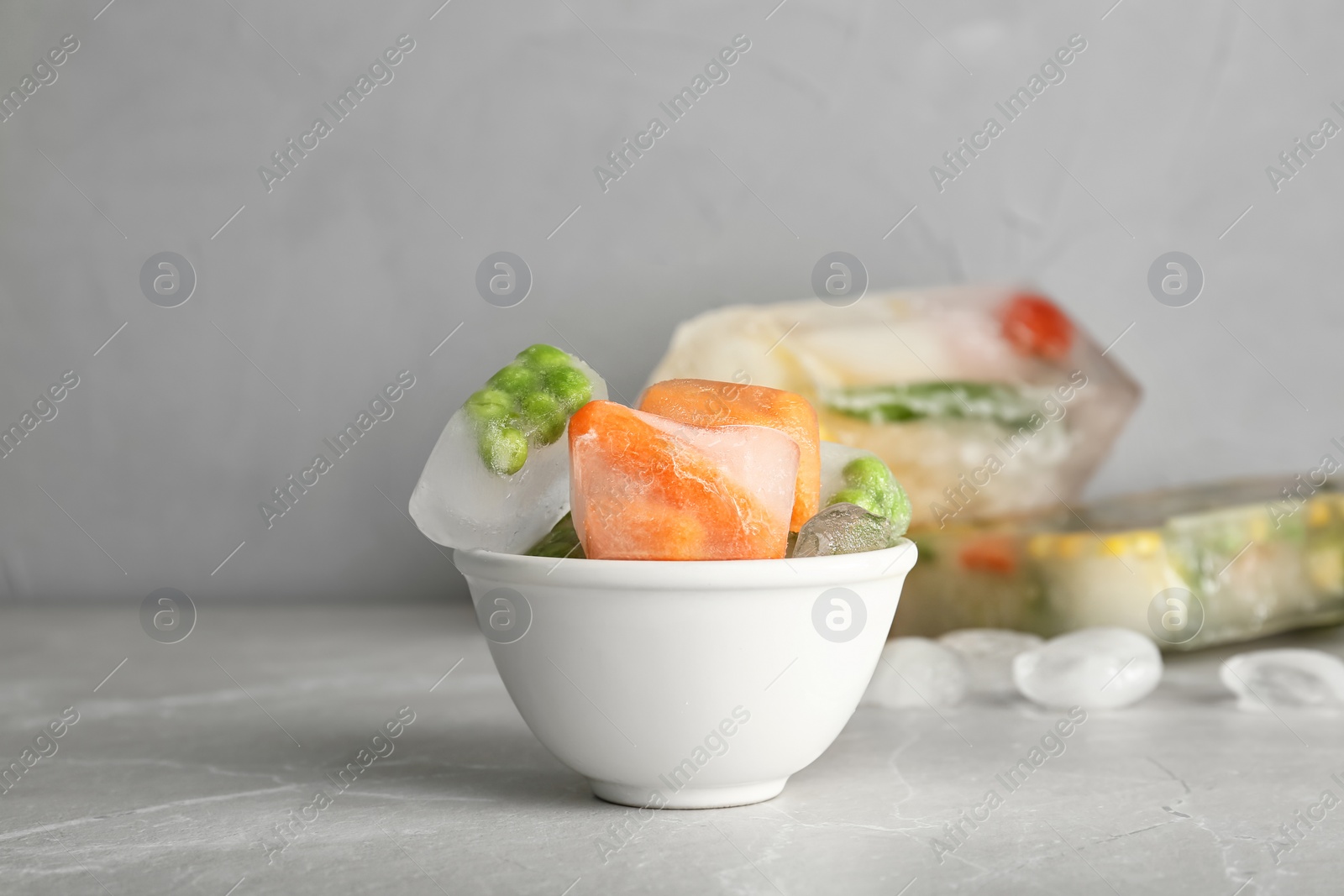 Photo of Bowl with frozen vegetables on gray table