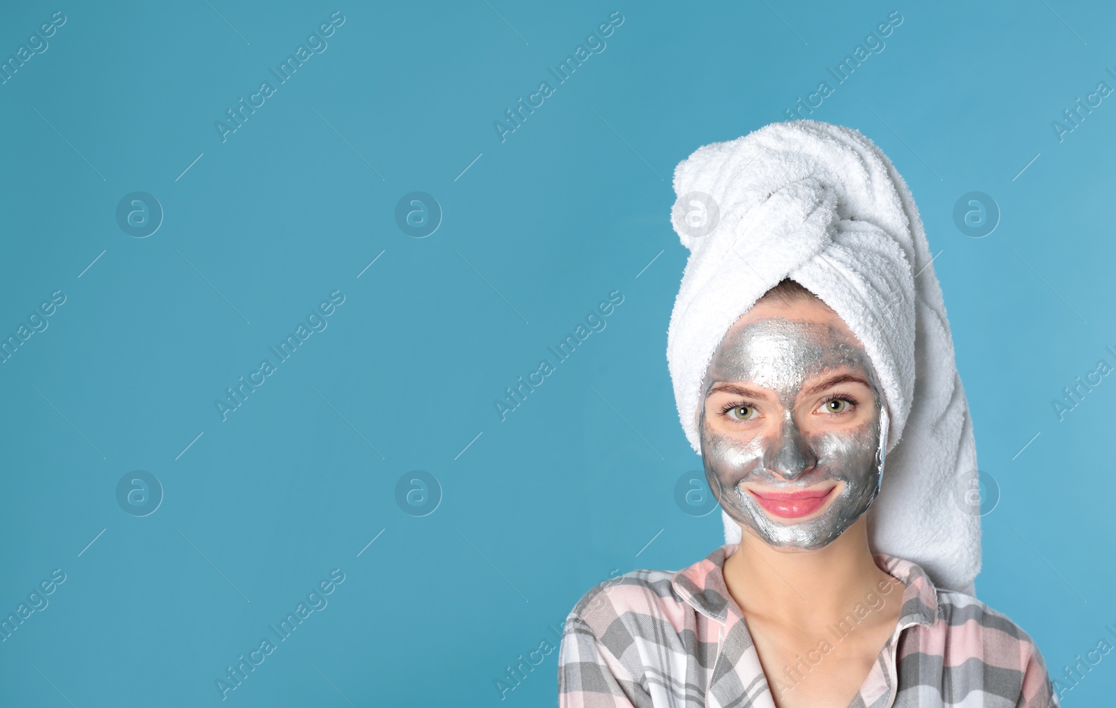 Photo of Young woman with cleansing mask on her face against color background, space for text. Skin care