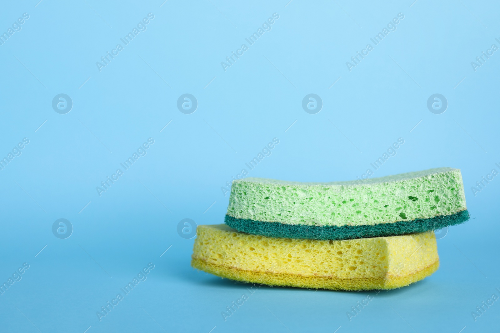 Photo of Two sponges on light blue background. Space for text