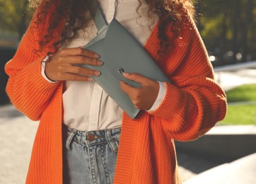 Young African American woman with stylish waist bag on city street, closeup