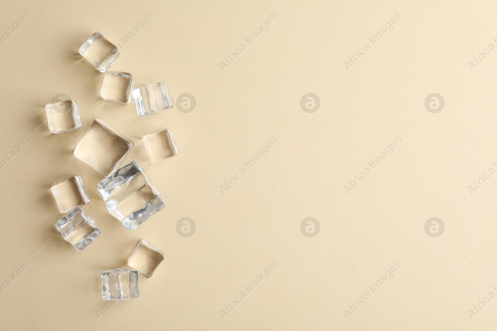 Photo of Crystal clear ice cubes on beige background, flat lay. Space for text