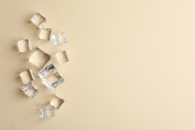 Crystal clear ice cubes on beige background, flat lay. Space for text