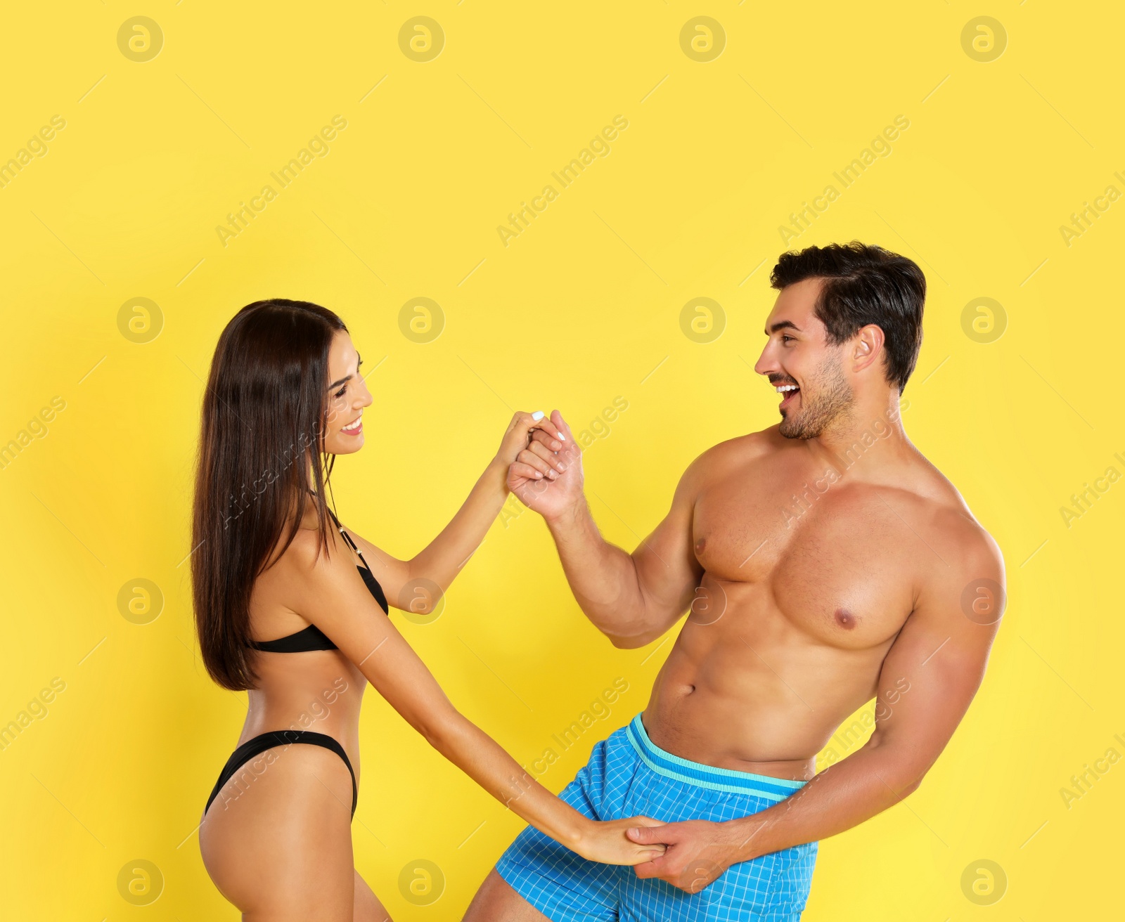 Photo of Young attractive couple in beachwear on yellow background