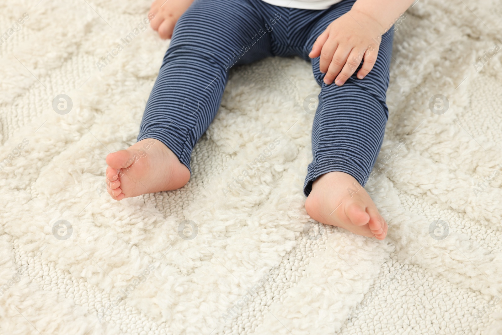 Photo of Baby sitting on soft carpet, closeup view