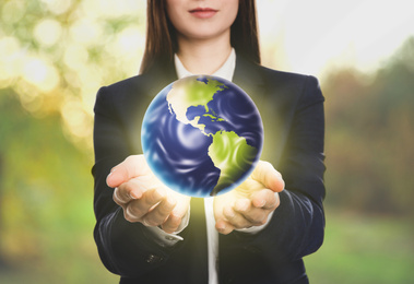 Young woman holding Earth outdoors, closeup view