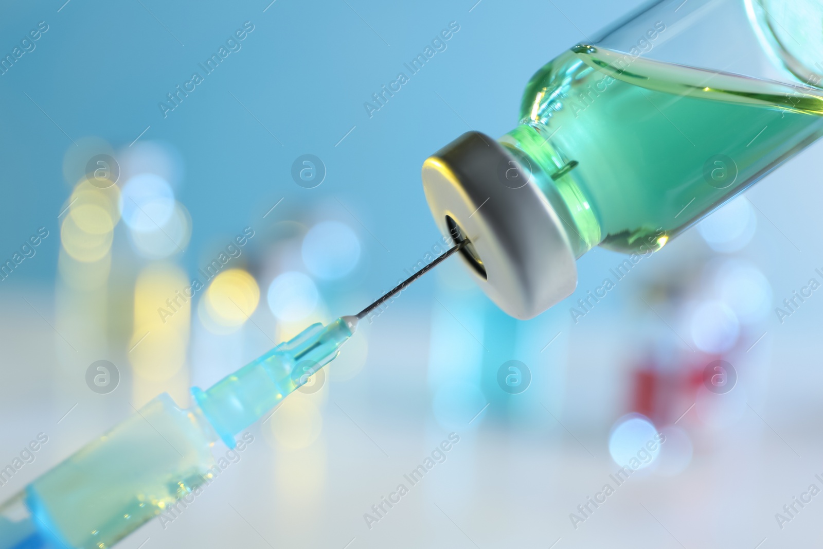 Photo of Filling syringe with medication from vial against blurred background, closeup. Vaccination and immunization