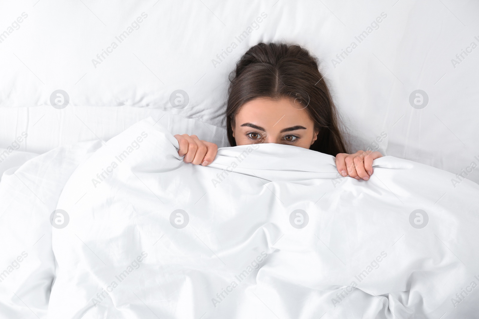 Photo of Young woman lying under blanket, top view. Bedtime