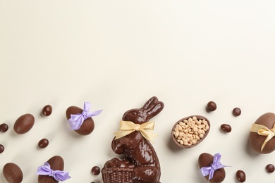 Photo of Flat lay composition with chocolate Easter bunny, eggs and candies on light background. Space for text