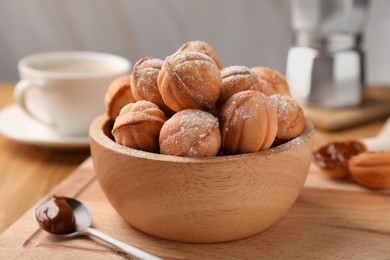 Photo of Bowl of delicious nut shaped cookies with boiled condensed milk on wooden table, closeup