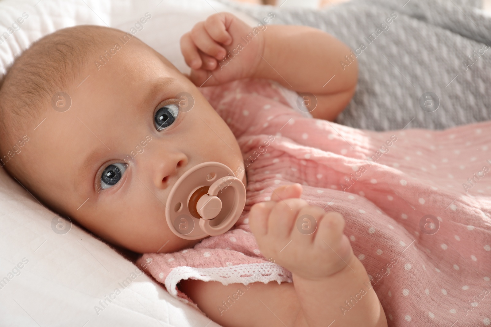 Photo of Cute little baby with pacifier lying in crib