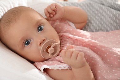 Cute little baby with pacifier lying in crib