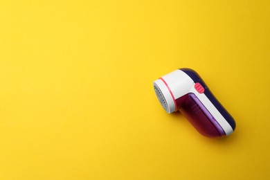 Modern fabric shaver on yellow background, top view. Space for text