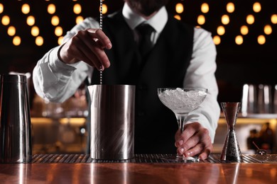 Photo of Bartender with martini glass preparing fresh alcoholic cocktail at bar counter, closeup