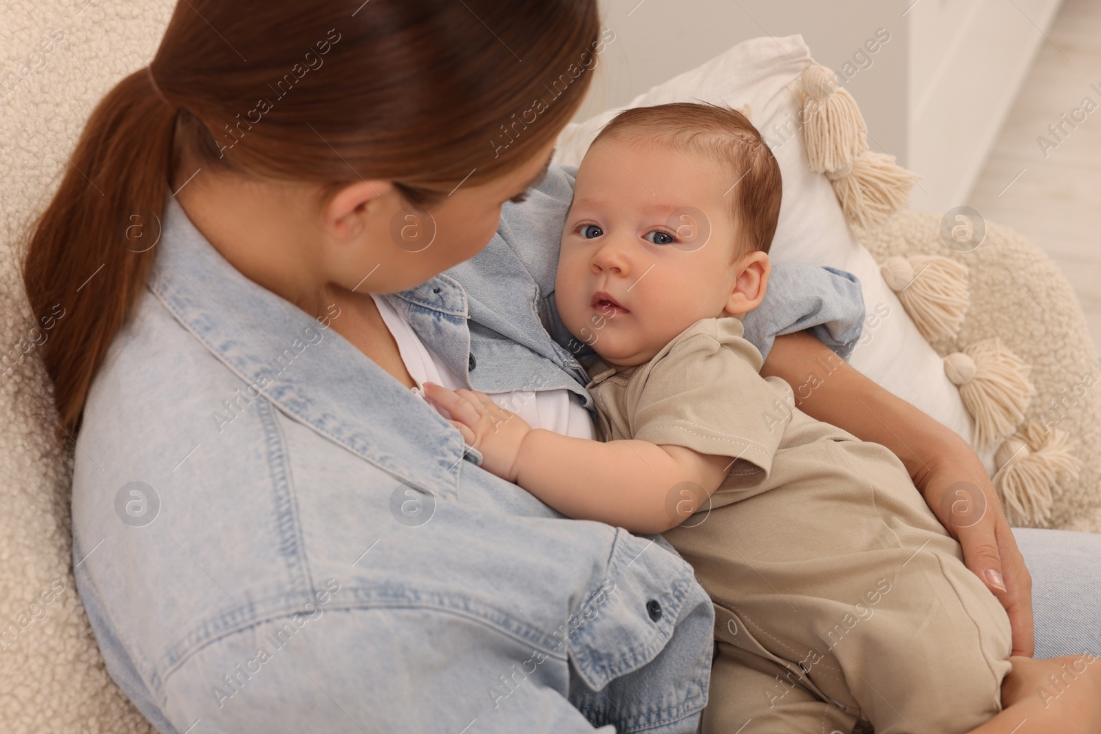 Photo of Mother holding her cute newborn baby in armchair indoors