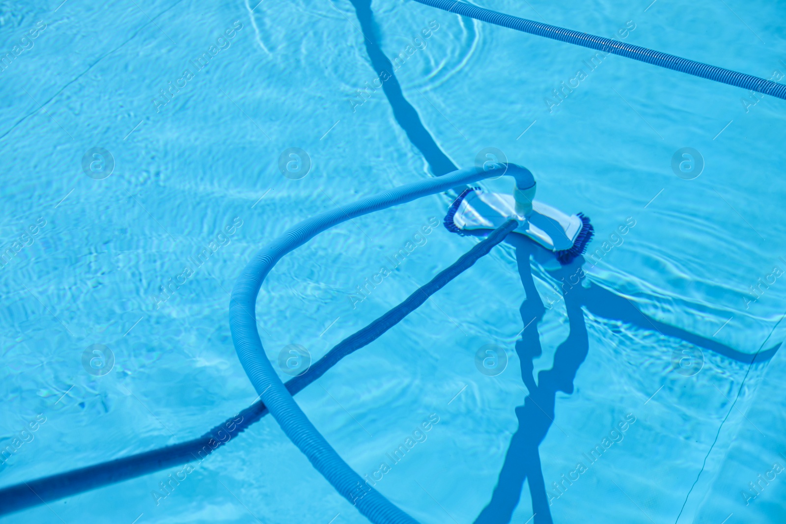 Photo of Cleaning outdoor pool with underwater vacuum, closeup