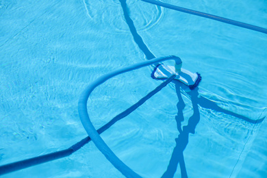 Photo of Cleaning outdoor pool with underwater vacuum, closeup