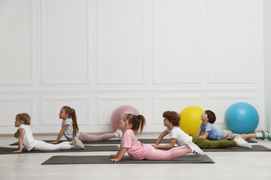 Group of children doing gymnastic exercises on mats indoors