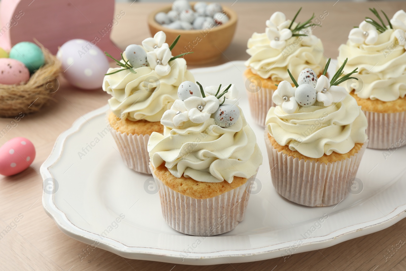 Photo of Tasty Easter cupcakes with vanilla cream on wooden table, closeup