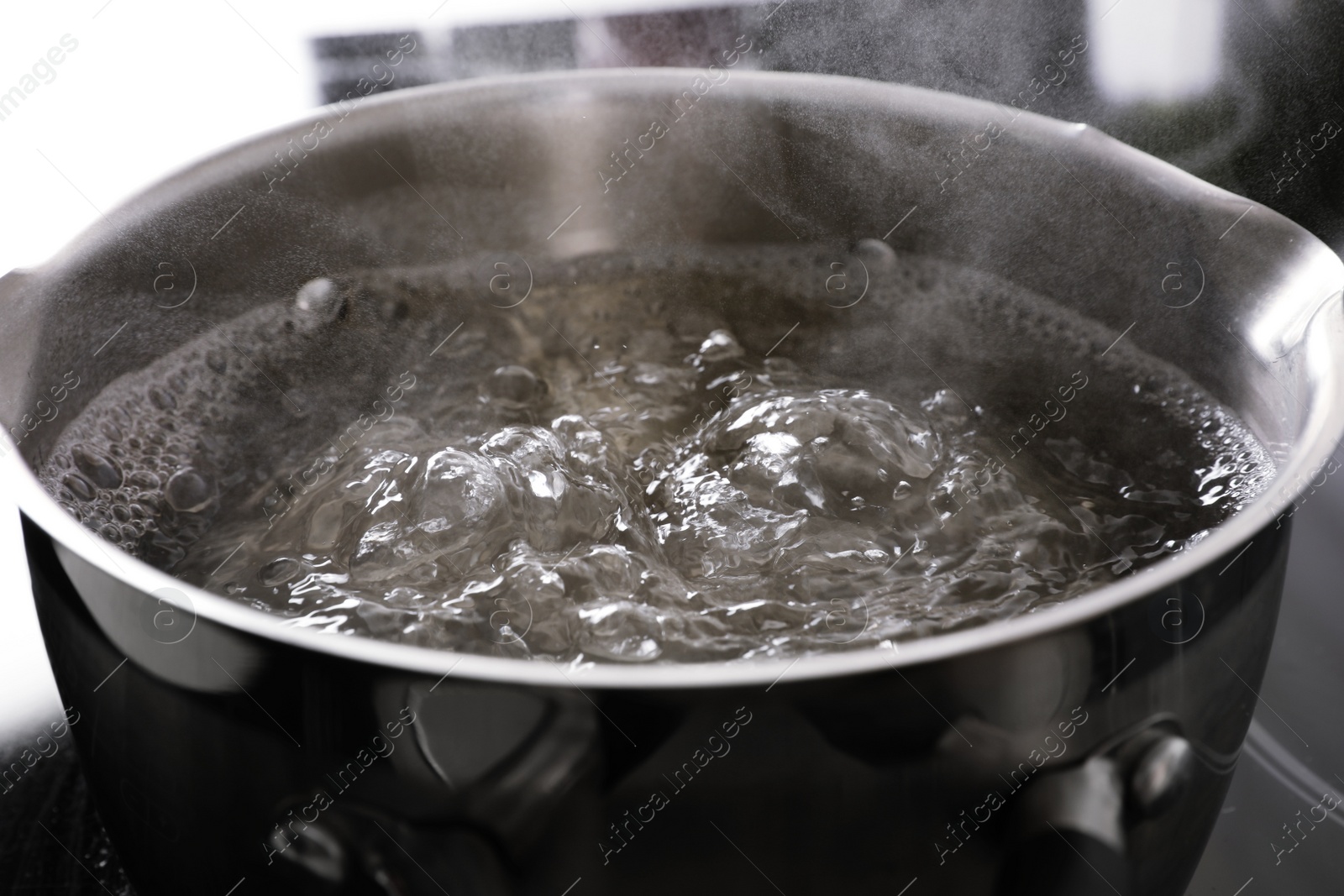 Photo of Pot with boiling water on stove, closeup