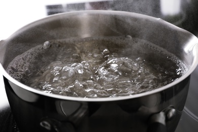 Pot with boiling water on stove, closeup