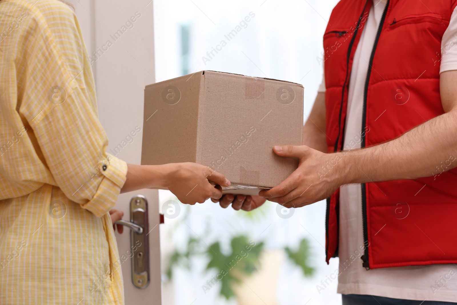Photo of Woman receiving parcel from deliveryman on blurred background, closeup. Space for text