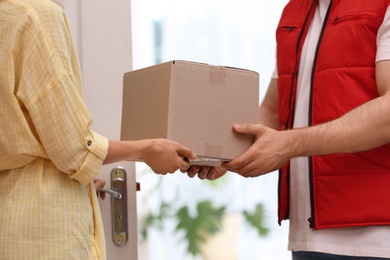 Woman receiving parcel from deliveryman on blurred background, closeup. Space for text