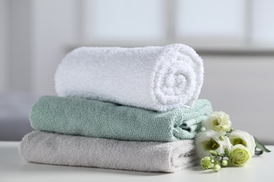 Photo of Stack of folded colorful towels with flowers on white table indoors, closeup
