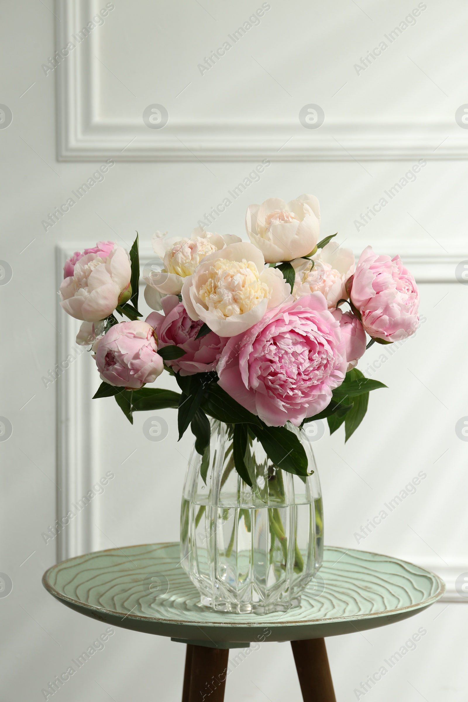 Photo of Beautiful peonies in glass vase on table