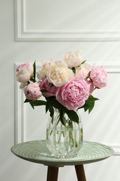 Beautiful peonies in glass vase on table