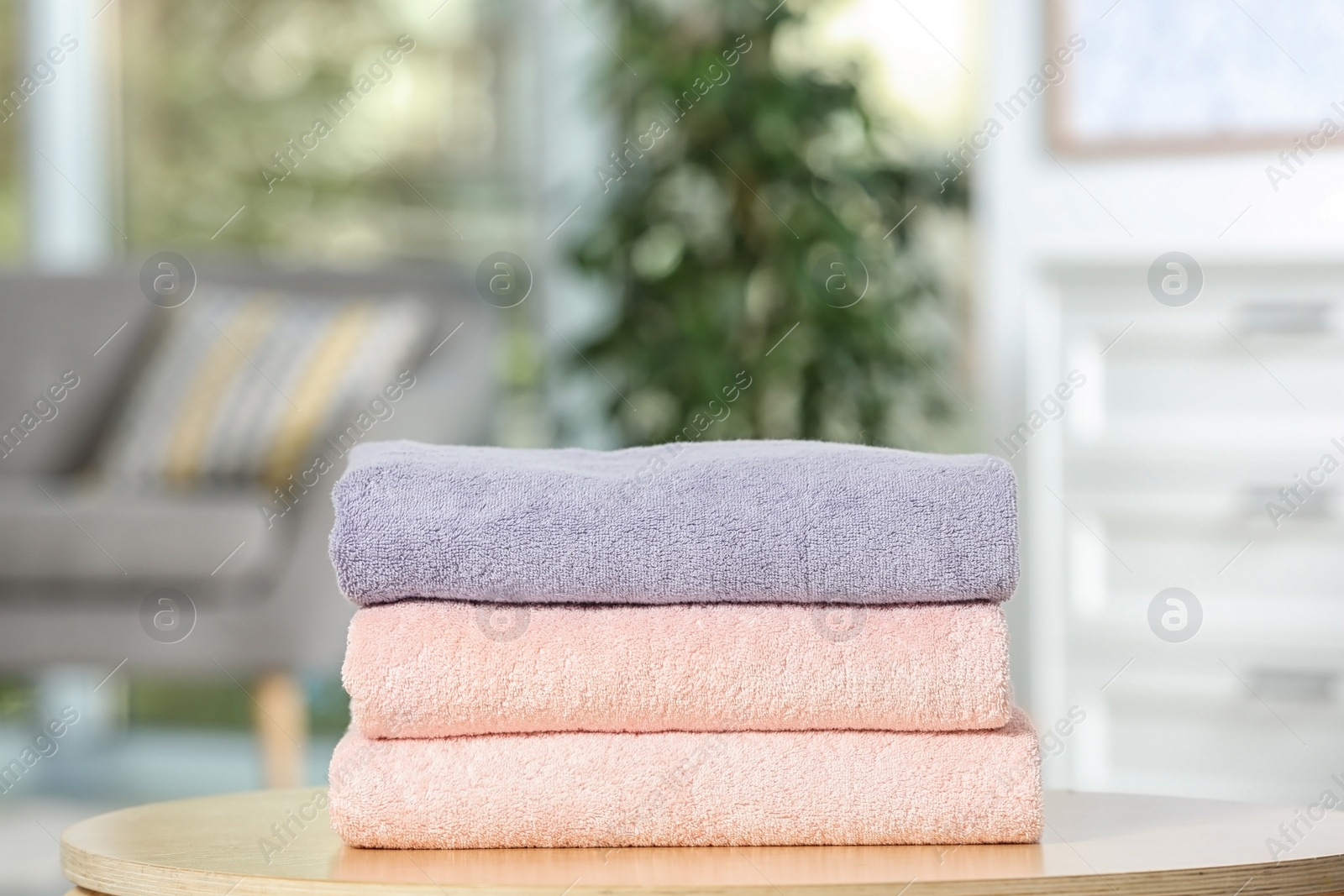 Photo of Stack of folded clean soft towels on table indoors