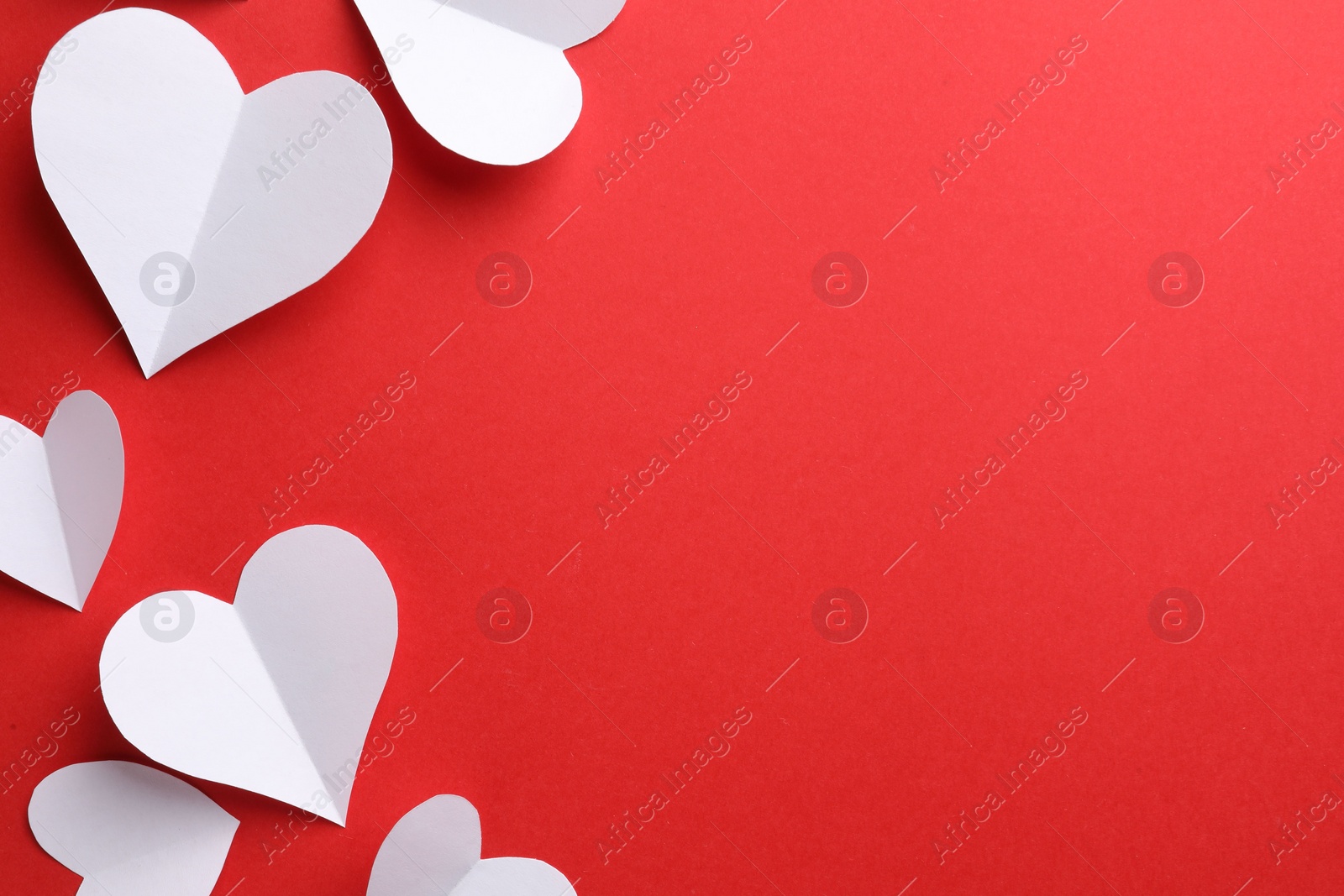 Photo of White paper hearts on red background, flat lay. Space for text